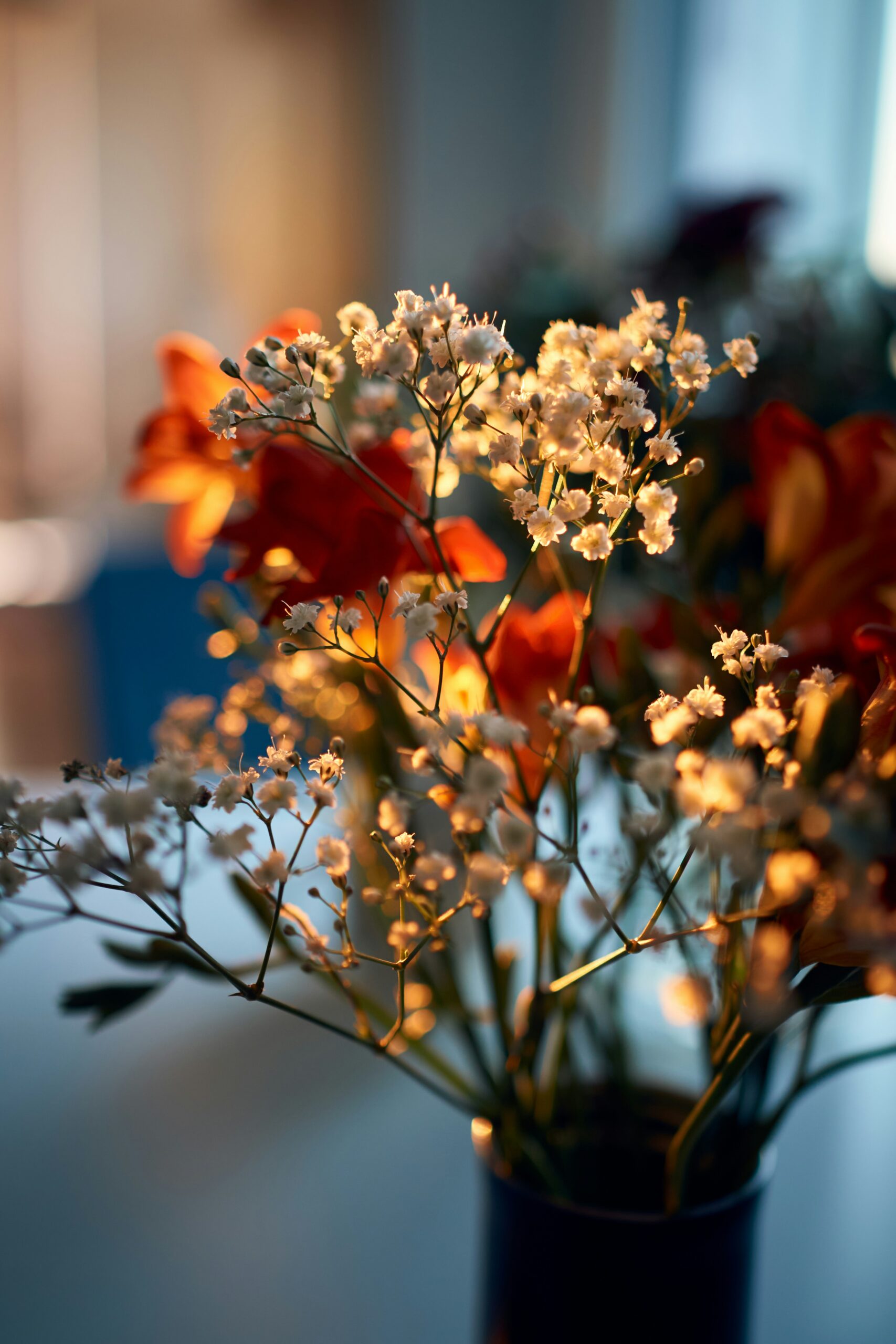 A warm, softly lit bouquet of orange lilies and white baby’s breath glowing in golden hour light, symbolizing calm summer evenings for moms.
